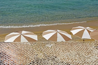 Sahilde dört şemsiye dalgaların arka planında