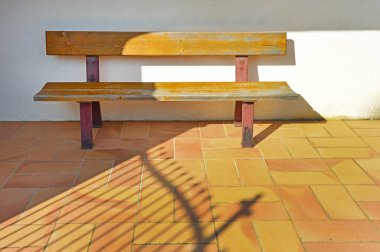 A large wooden bench is half covered by shadow clipart