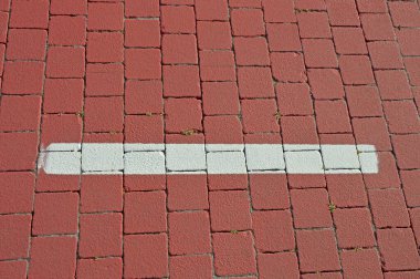 Kare terracotta parke taşında beyaz yol işaretleri