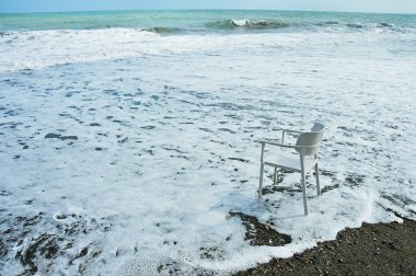 Deniz kıyısındaki yalnız, beyaz plastik sandalye