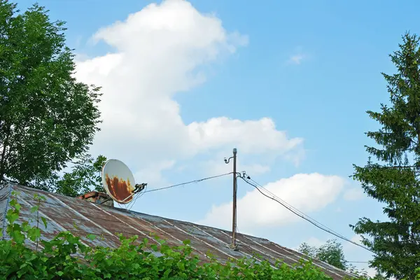 Eski bir evin çatısında paslanmış uydu televizyon anteni.