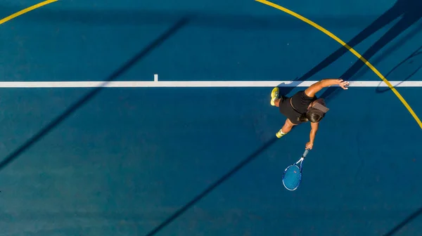 在一个全新的球场上 一个年轻的女网球选手正在行动 鸟瞰全景 这张照片是用无人驾驶飞机拍摄的 为游戏提供了独特的视角 — 图库照片