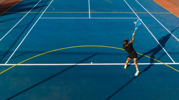 在一个全新的球场上 一个年轻的女网球选手正在行动 鸟瞰全景 这张照片是用无人驾驶飞机拍摄的 为游戏提供了独特的视角 — 图库照片