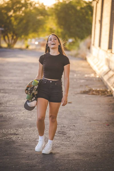 在一个充满活力的城市环境中 漂亮的年轻女子 黑发滑板 — 图库照片