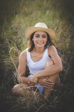 Uzun siyah saçlı, uzun çimenli bir arazide güzel bir genç kadın.. 