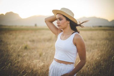 Uzun siyah saçlı, uzun çimenli bir arazide güzel bir genç kadın.. 