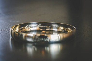 Nikah yüzüklerinin bu çarpıcı yakın plan görüntüsü, sevgi dolu düğün geleneğinin güzelliğini ve sembolizmini yansıtıyor. Fotoğrafta gelinin ve damadın alyansları tarafsız bir zemine yerleştirilmiş. Karmaşık detayları vurguluyor.