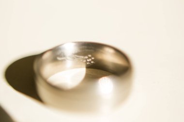 Nikah yüzüklerinin bu çarpıcı yakın plan görüntüsü, sevgi dolu düğün geleneğinin güzelliğini ve sembolizmini yansıtıyor. Fotoğrafta gelinin ve damadın alyansları tarafsız bir zemine yerleştirilmiş. Karmaşık detayları vurguluyor.