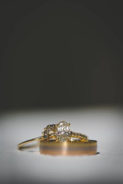 Nikah yüzüklerinin bu çarpıcı yakın plan görüntüsü, sevgi dolu düğün geleneğinin güzelliğini ve sembolizmini yansıtıyor. Fotoğrafta gelinin ve damadın alyansları tarafsız bir zemine yerleştirilmiş. Karmaşık detayları vurguluyor.