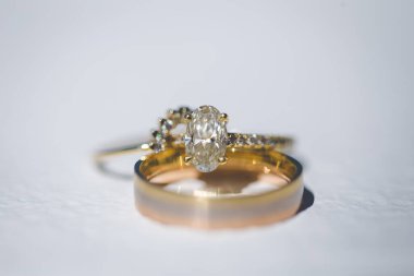 Nikah yüzüklerinin bu çarpıcı yakın plan görüntüsü, sevgi dolu düğün geleneğinin güzelliğini ve sembolizmini yansıtıyor. Fotoğrafta gelinin ve damadın alyansları tarafsız bir zemine yerleştirilmiş. Karmaşık detayları vurguluyor.