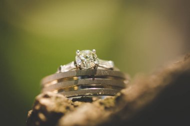 Nikah yüzüklerinin bu çarpıcı yakın plan görüntüsü, sevgi dolu düğün geleneğinin güzelliğini ve sembolizmini yansıtıyor. Fotoğrafta gelinin ve damadın alyansları tarafsız bir zemine yerleştirilmiş. Karmaşık detayları vurguluyor.