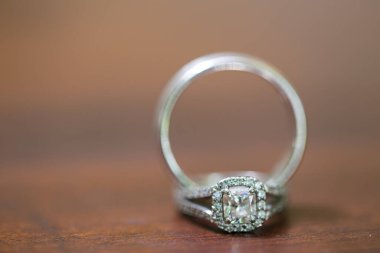 Nikah yüzüklerinin bu çarpıcı yakın plan görüntüsü, sevgi dolu düğün geleneğinin güzelliğini ve sembolizmini yansıtıyor. Fotoğrafta gelinin ve damadın alyansları tarafsız bir zemine yerleştirilmiş. Karmaşık detayları vurguluyor.