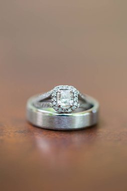 Nikah yüzüklerinin bu çarpıcı yakın plan görüntüsü, sevgi dolu düğün geleneğinin güzelliğini ve sembolizmini yansıtıyor. Fotoğrafta gelinin ve damadın alyansları tarafsız bir zemine yerleştirilmiş. Karmaşık detayları vurguluyor.