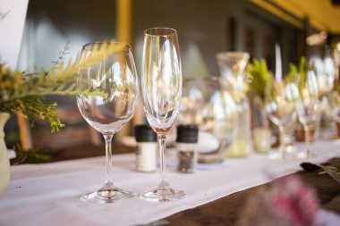 Bu büyüleyici görüntü, gerçek bir düğünün zarif dekorunu ve büyüleyici çiçek düzenlemelerini gözler önüne seriyor. Fotoğrafta zarif çiçekler, mumlar ve diğer dekoratif el ile süslenmiş büyüleyici bir düğün yerinde güzel dekore edilmiş bir masa yer alıyor.