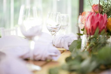 Bu büyüleyici görüntü, gerçek bir düğünün zarif dekorunu ve büyüleyici çiçek düzenlemelerini gözler önüne seriyor. Fotoğrafta zarif çiçekler, mumlar ve diğer dekoratif el ile süslenmiş büyüleyici bir düğün yerinde güzel dekore edilmiş bir masa yer alıyor.