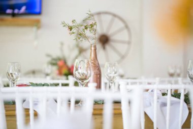 Bu büyüleyici görüntü, gerçek bir düğünün zarif dekorunu ve büyüleyici çiçek düzenlemelerini gözler önüne seriyor. Fotoğrafta zarif çiçekler, mumlar ve diğer dekoratif el ile süslenmiş büyüleyici bir düğün yerinde güzel dekore edilmiş bir masa yer alıyor.