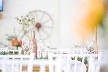 Bu büyüleyici görüntü, gerçek bir düğünün zarif dekorunu ve büyüleyici çiçek düzenlemelerini gözler önüne seriyor. Fotoğrafta zarif çiçekler, mumlar ve diğer dekoratif el ile süslenmiş büyüleyici bir düğün yerinde güzel dekore edilmiş bir masa yer alıyor.