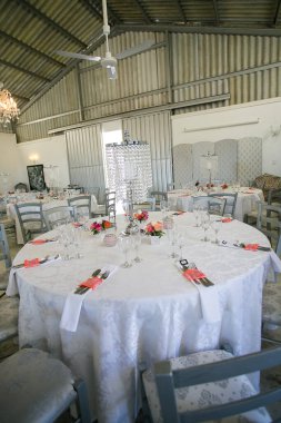 Bu büyüleyici görüntü, gerçek bir düğünün zarif dekorunu ve büyüleyici çiçek düzenlemelerini gözler önüne seriyor. Fotoğrafta zarif çiçekler, mumlar ve diğer dekoratif el ile süslenmiş büyüleyici bir düğün yerinde güzel dekore edilmiş bir masa yer alıyor.