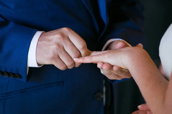この美しいイメージは 実際の結婚式で結婚指輪を交換するカップルの親密な瞬間を捉えます 写真はカップルの手の近くにあり 彼らの絡み合った指と結婚指輪を指に見せています — ストック写真