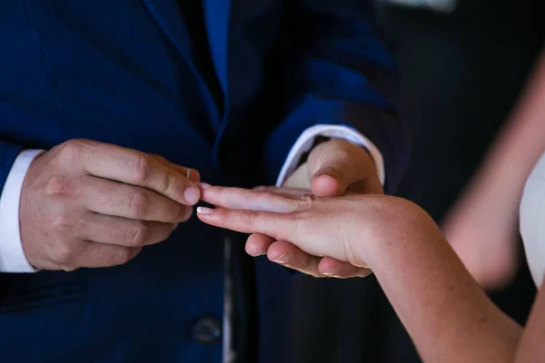 この美しいイメージは 実際の結婚式で結婚指輪を交換するカップルの親密な瞬間を捉えます 写真はカップルの手の近くにあり 彼らの絡み合った指と結婚指輪を指に見せています — ストック写真