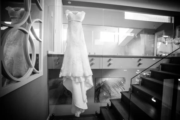 This captivating image showcases a wedding dress with intricate details photographed in creative and unique ways. The photograph features a stunning white wedding dress with intricate lace detailing and delicate beading. The dress is photographed fro