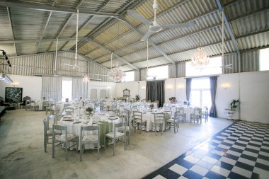 Bu büyüleyici görüntü, gerçek bir düğünün zarif dekorunu ve büyüleyici çiçek düzenlemelerini gözler önüne seriyor. Fotoğrafta zarif çiçekler, mumlar ve diğer dekoratif el ile süslenmiş büyüleyici bir düğün yerinde güzel dekore edilmiş bir masa yer alıyor.