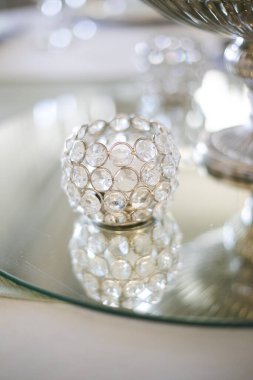 Bu büyüleyici görüntü, gerçek bir düğünün zarif dekorunu ve büyüleyici çiçek düzenlemelerini gözler önüne seriyor. Fotoğrafta zarif çiçekler, mumlar ve diğer dekoratif el ile süslenmiş büyüleyici bir düğün yerinde güzel dekore edilmiş bir masa yer alıyor.