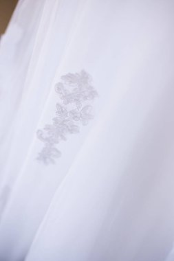 Bu büyüleyici görüntü, yaratıcı ve benzersiz bir şekilde fotoğraflanmış karmaşık detaylarla dolu bir gelinlik sergiliyor. Fotoğrafta karmaşık dantelli ve narin boncuklu çarpıcı beyaz bir gelinlik yer alıyor. Elbisenin fro fotografı var.