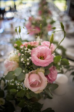 Bu büyüleyici görüntü, gerçek bir düğünün zarif dekorunu ve büyüleyici çiçek düzenlemelerini gözler önüne seriyor. Fotoğrafta zarif çiçekler, mumlar ve diğer dekoratif el ile süslenmiş büyüleyici bir düğün yerinde güzel dekore edilmiş bir masa yer alıyor.