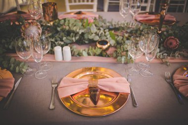 Bu büyüleyici görüntü, gerçek bir düğünün zarif dekorunu ve büyüleyici çiçek düzenlemelerini gözler önüne seriyor. Fotoğrafta zarif çiçekler, mumlar ve diğer dekoratif el ile süslenmiş büyüleyici bir düğün yerinde güzel dekore edilmiş bir masa yer alıyor.