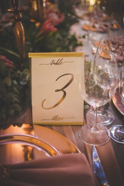 Bu büyüleyici görüntü, gerçek bir düğünün zarif dekorunu ve büyüleyici çiçek düzenlemelerini gözler önüne seriyor. Fotoğrafta zarif çiçekler, mumlar ve diğer dekoratif el ile süslenmiş büyüleyici bir düğün yerinde güzel dekore edilmiş bir masa yer alıyor.