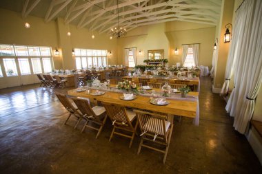 Bu büyüleyici görüntü, gerçek bir düğünün zarif dekorunu ve büyüleyici çiçek düzenlemelerini gözler önüne seriyor. Fotoğrafta zarif çiçekler, mumlar ve diğer dekoratif el ile süslenmiş büyüleyici bir düğün yerinde güzel dekore edilmiş bir masa yer alıyor.