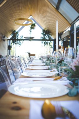 Bu büyüleyici görüntü, gerçek bir düğünün zarif dekorunu ve büyüleyici çiçek düzenlemelerini gözler önüne seriyor. Fotoğrafta zarif çiçekler, mumlar ve diğer dekoratif el ile süslenmiş büyüleyici bir düğün yerinde güzel dekore edilmiş bir masa yer alıyor.