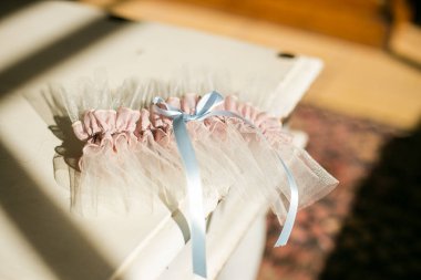 Bu büyüleyici görüntü, küpe, ayakkabı, jartiyer, mücevher ve parfüm gibi gelin aksesuarlarının yaratıcı ve sanatsal bir fotoğrafını sergiliyor. Fotoğraf çeşitli elementlerin güzel bir bileşimidir, karmaşık ayrıntıları vurgular. 