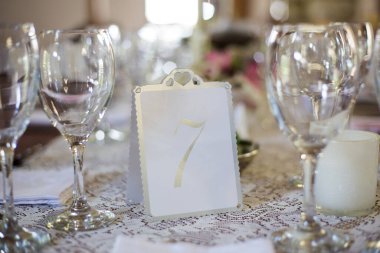 Bu büyüleyici görüntü, gerçek bir düğünün zarif dekorunu ve büyüleyici çiçek düzenlemelerini gözler önüne seriyor. Fotoğrafta zarif çiçekler, mumlar ve diğer dekoratif el ile süslenmiş büyüleyici bir düğün yerinde güzel dekore edilmiş bir masa yer alıyor.