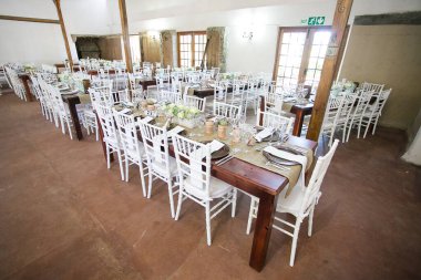 Bu büyüleyici görüntü, gerçek bir düğünün zarif dekorunu ve büyüleyici çiçek düzenlemelerini gözler önüne seriyor. Fotoğrafta zarif çiçekler, mumlar ve diğer dekoratif el ile süslenmiş büyüleyici bir düğün yerinde güzel dekore edilmiş bir masa yer alıyor.