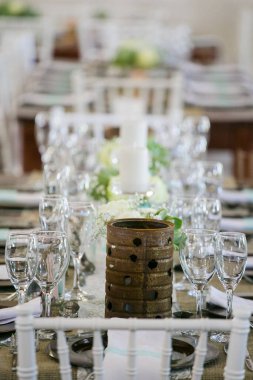 Bu büyüleyici görüntü, gerçek bir düğünün zarif dekorunu ve büyüleyici çiçek düzenlemelerini gözler önüne seriyor. Fotoğrafta zarif çiçekler, mumlar ve diğer dekoratif el ile süslenmiş büyüleyici bir düğün yerinde güzel dekore edilmiş bir masa yer alıyor.