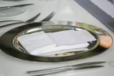 Bu büyüleyici görüntü, gerçek bir düğünün zarif dekorunu ve büyüleyici çiçek düzenlemelerini gözler önüne seriyor. Fotoğrafta zarif çiçekler, mumlar ve diğer dekoratif el ile süslenmiş büyüleyici bir düğün yerinde güzel dekore edilmiş bir masa yer alıyor.