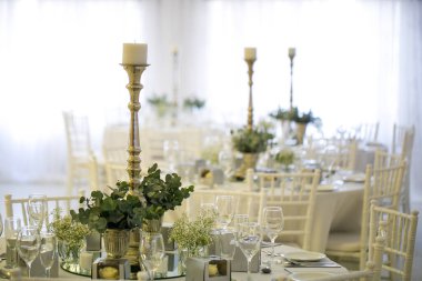 Bu büyüleyici görüntü, gerçek bir düğünün zarif dekorunu ve büyüleyici çiçek düzenlemelerini gözler önüne seriyor. Fotoğrafta zarif çiçekler, mumlar ve diğer dekoratif el ile süslenmiş büyüleyici bir düğün yerinde güzel dekore edilmiş bir masa yer alıyor.