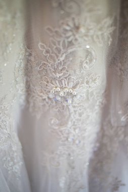 Bu büyüleyici görüntü, yaratıcı ve benzersiz bir şekilde fotoğraflanmış karmaşık detaylarla dolu bir gelinlik sergiliyor. Fotoğrafta karmaşık dantelli ve narin boncuklu çarpıcı beyaz bir gelinlik yer alıyor. Elbisenin fro fotografı var.