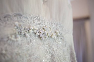 Bu büyüleyici görüntü, yaratıcı ve benzersiz bir şekilde fotoğraflanmış karmaşık detaylarla dolu bir gelinlik sergiliyor. Fotoğrafta karmaşık dantelli ve narin boncuklu çarpıcı beyaz bir gelinlik yer alıyor. Elbisenin fro fotografı var.