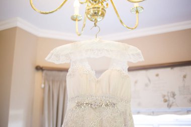 Bu büyüleyici görüntü, yaratıcı ve benzersiz bir şekilde fotoğraflanmış karmaşık detaylarla dolu bir gelinlik sergiliyor. Fotoğrafta karmaşık dantelli ve narin boncuklu çarpıcı beyaz bir gelinlik yer alıyor. Elbisenin fro fotografı var.