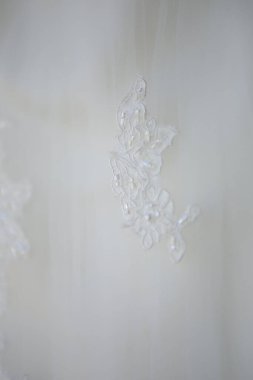 Bu büyüleyici görüntü, yaratıcı ve benzersiz bir şekilde fotoğraflanmış karmaşık detaylarla dolu bir gelinlik sergiliyor. Fotoğrafta karmaşık dantelli ve narin boncuklu çarpıcı beyaz bir gelinlik yer alıyor. Elbisenin fro fotografı var.