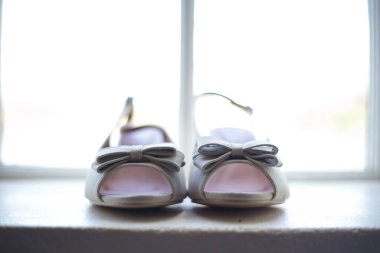 Bu büyüleyici görüntü, küpe, ayakkabı, jartiyer, mücevher ve parfüm gibi gelin aksesuarlarının yaratıcı ve sanatsal bir fotoğrafını sergiliyor. Fotoğraf çeşitli elementlerin güzel bir bileşimidir, karmaşık ayrıntıları vurgular. 