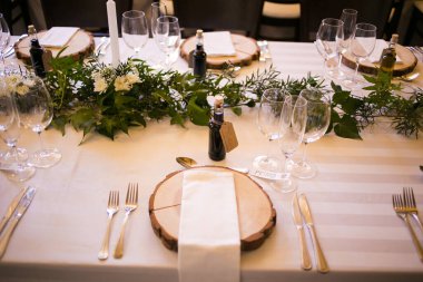 Bu büyüleyici görüntü, gerçek bir düğünün zarif dekorunu ve büyüleyici çiçek düzenlemelerini gözler önüne seriyor. Fotoğrafta zarif çiçekler, mumlar ve diğer dekoratif el ile süslenmiş büyüleyici bir düğün yerinde güzel dekore edilmiş bir masa yer alıyor.