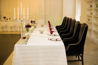 Bu büyüleyici görüntü, gerçek bir düğünün zarif dekorunu ve büyüleyici çiçek düzenlemelerini gözler önüne seriyor. Fotoğrafta zarif çiçekler, mumlar ve diğer dekoratif el ile süslenmiş büyüleyici bir düğün yerinde güzel dekore edilmiş bir masa yer alıyor.