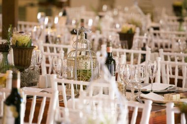 Bu büyüleyici görüntü, gerçek bir düğünün zarif dekorunu ve büyüleyici çiçek düzenlemelerini gözler önüne seriyor. Fotoğrafta zarif çiçekler, mumlar ve diğer dekoratif el ile süslenmiş büyüleyici bir düğün yerinde güzel dekore edilmiş bir masa yer alıyor.