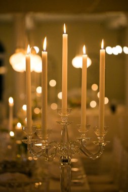 Bu büyüleyici görüntü, gerçek bir düğünün zarif dekorunu ve büyüleyici çiçek düzenlemelerini gözler önüne seriyor. Fotoğrafta zarif çiçekler, mumlar ve diğer dekoratif el ile süslenmiş büyüleyici bir düğün yerinde güzel dekore edilmiş bir masa yer alıyor.