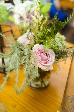 Bu büyüleyici görüntü, gerçek bir düğünün zarif dekorunu ve büyüleyici çiçek düzenlemelerini gözler önüne seriyor. Fotoğrafta zarif çiçekler, mumlar ve diğer dekoratif el ile süslenmiş büyüleyici bir düğün yerinde güzel dekore edilmiş bir masa yer alıyor.