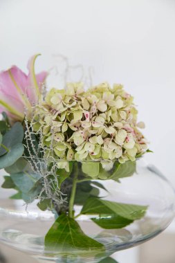 Bu büyüleyici görüntü, gerçek bir düğünün zarif dekorunu ve büyüleyici çiçek düzenlemelerini gözler önüne seriyor. Fotoğrafta zarif çiçekler, mumlar ve diğer dekoratif el ile süslenmiş büyüleyici bir düğün yerinde güzel dekore edilmiş bir masa yer alıyor.